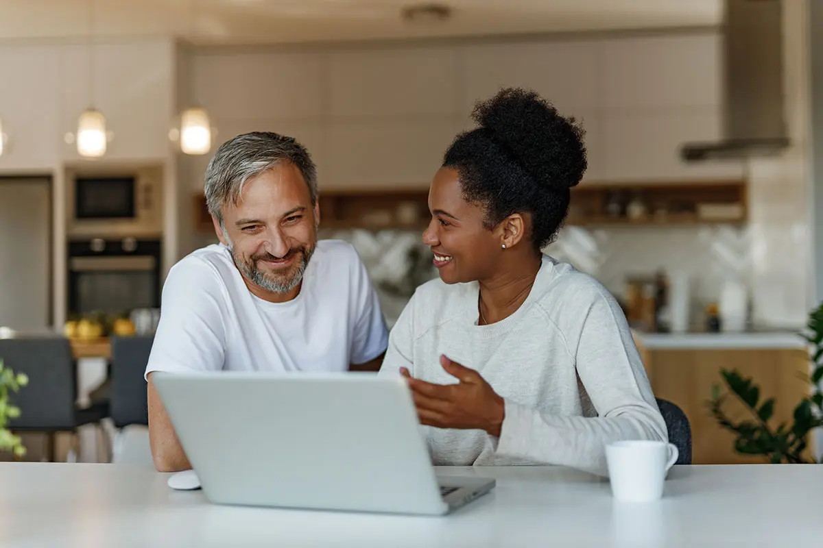 Adoptive couple creating their adoption profile together on a laptop at home.